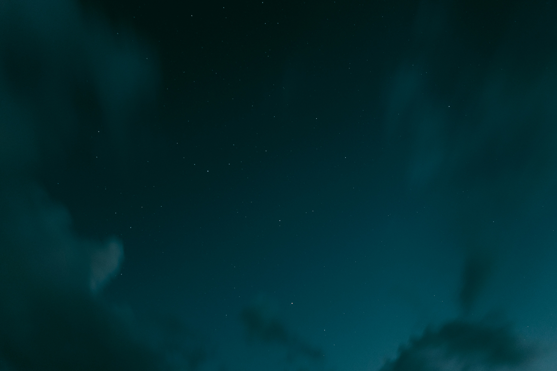 Deep teal night sky scattered with stars and drifting clouds